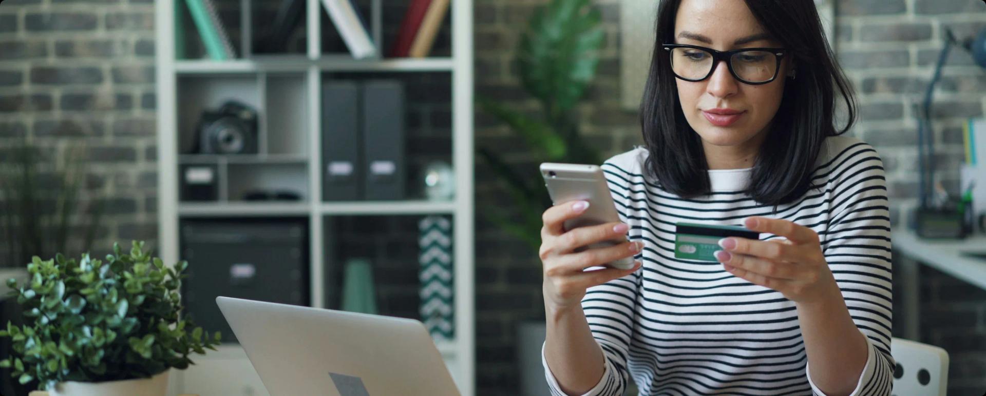 A woman reviewing costs with her bank card and phone